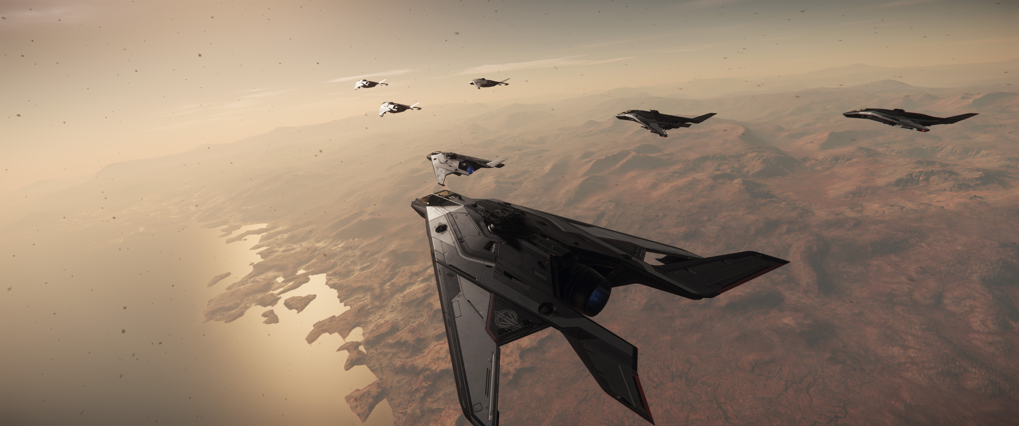 A squadron of Star Citizen fighter jets soaring across a desert terrain.